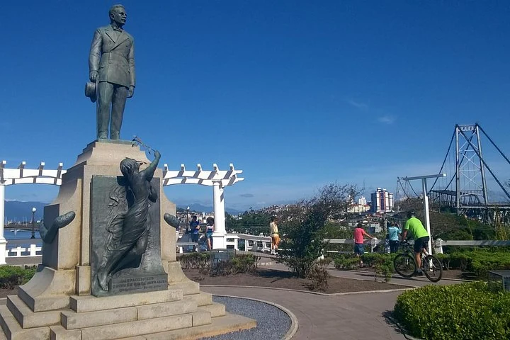 Monument in a square with Hercílio Luz Bridge in the background