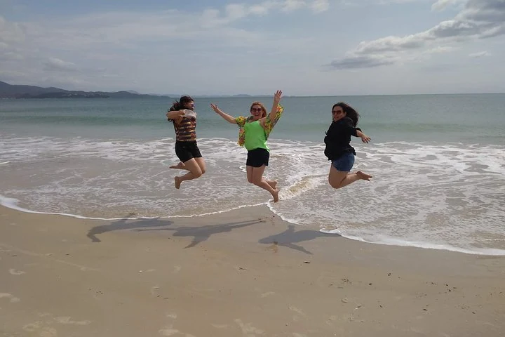 Three travellers jumping by the sea on a northern Florianópolis beach
