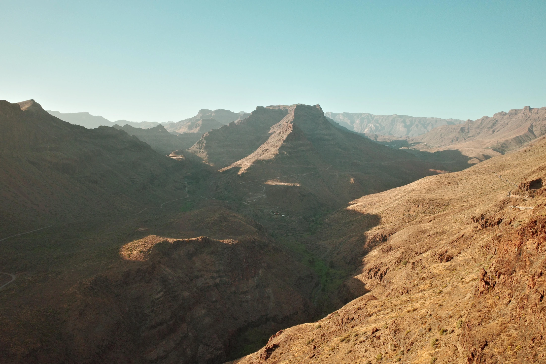 Vue sur une vallée montagneuse sèche aux crêtes et versants éclairés
