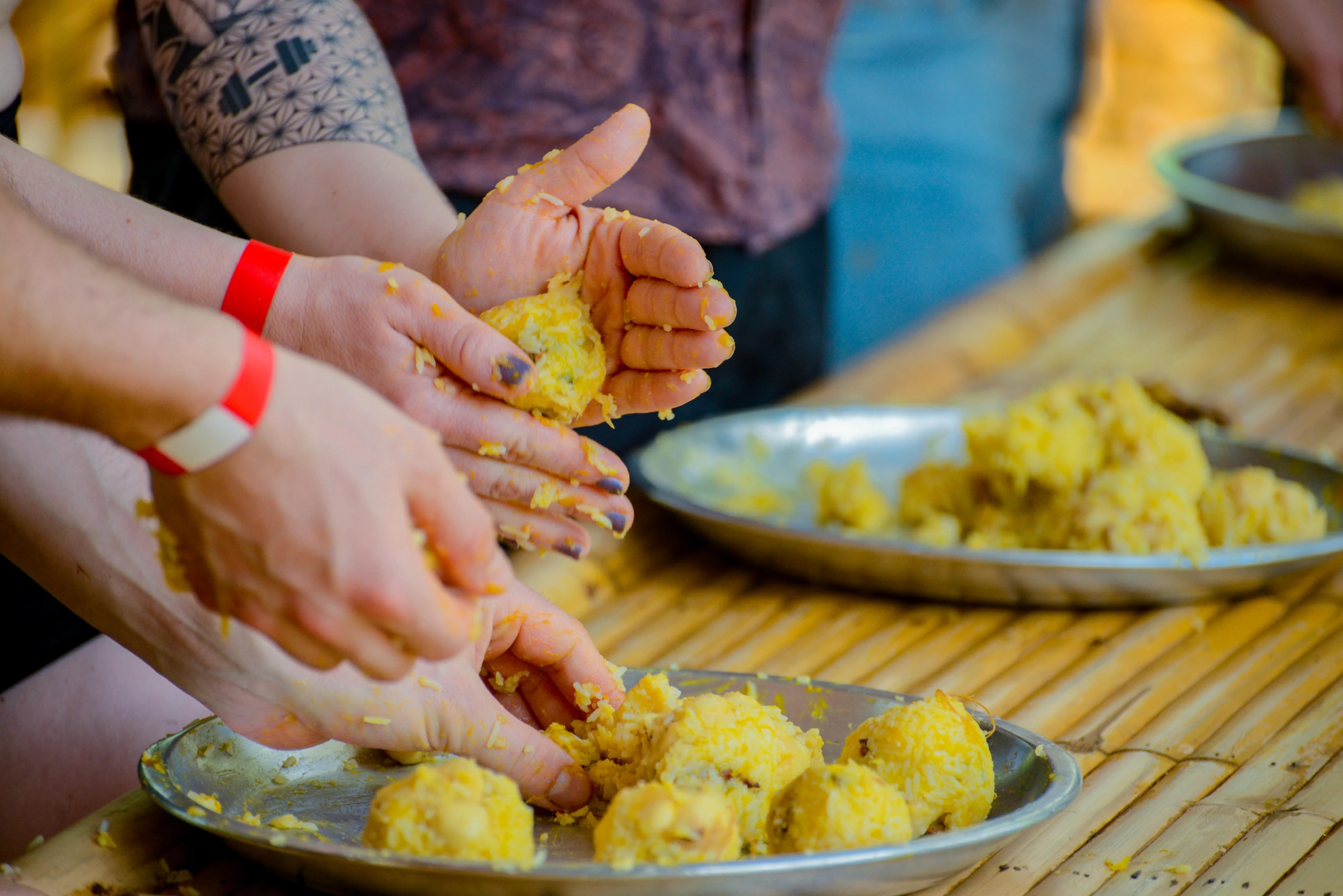Hands shaping yellow food balls on trays during an elephant activity.