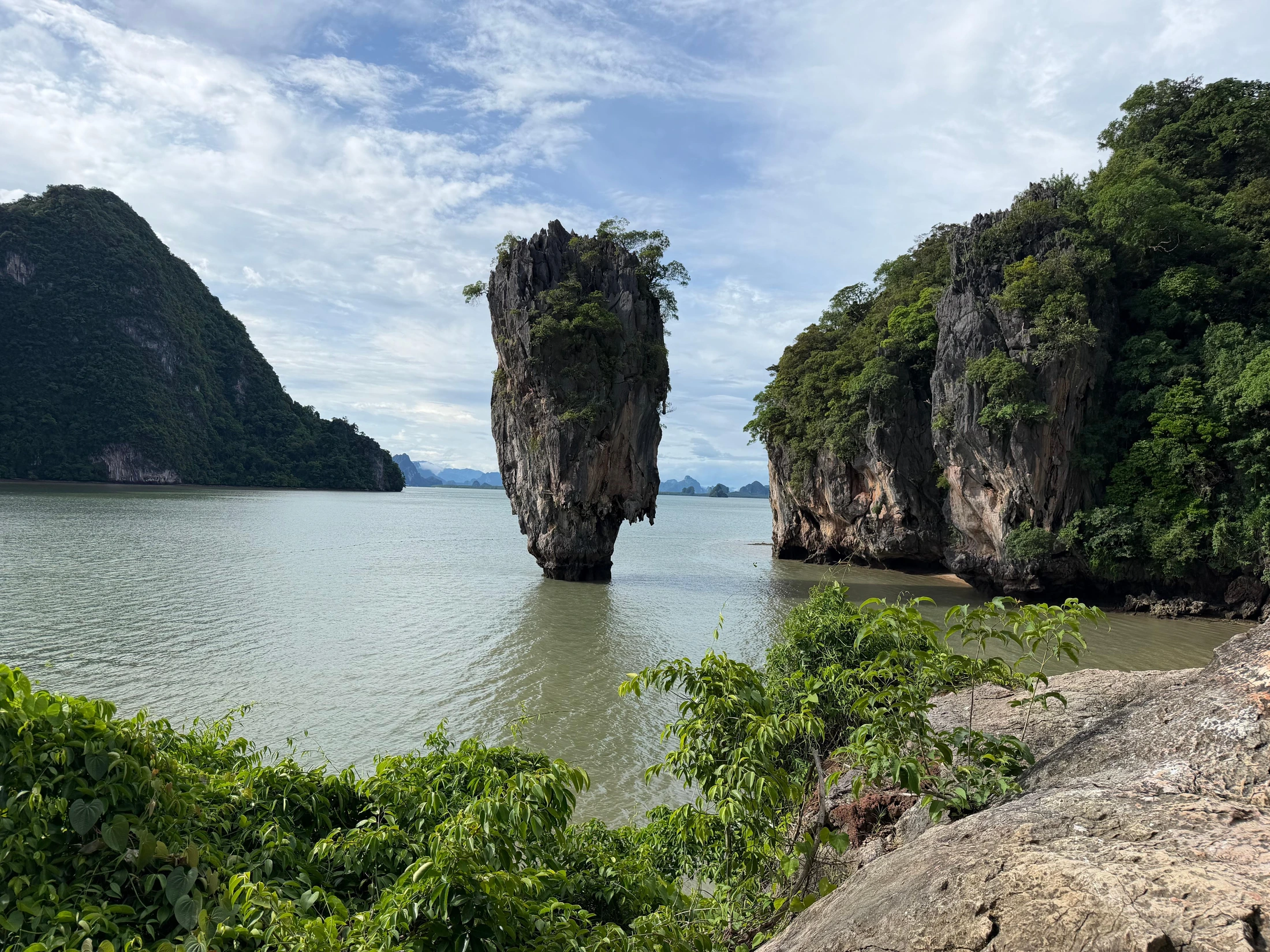 Ko Tapu rock in Phang Nga Bay beneath a cloudy sky.