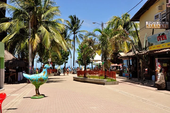 Fußgängerzone mit Lokalen und Hühnerskulptur in Porto de Galinhas