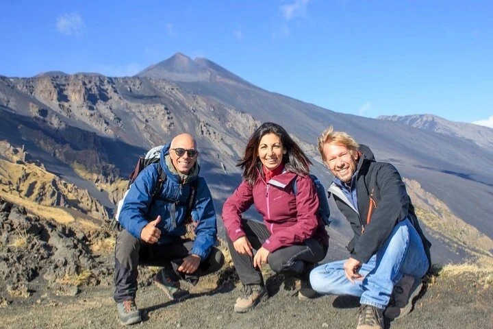 Three people in front of Etna’s volcanic terrain and cones