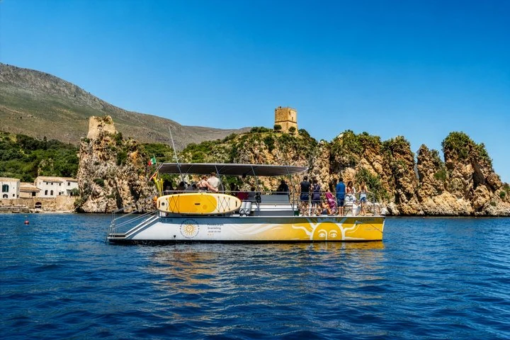 Side view of a catamaran beside Scopello’s tuna fishery and sea stacks
