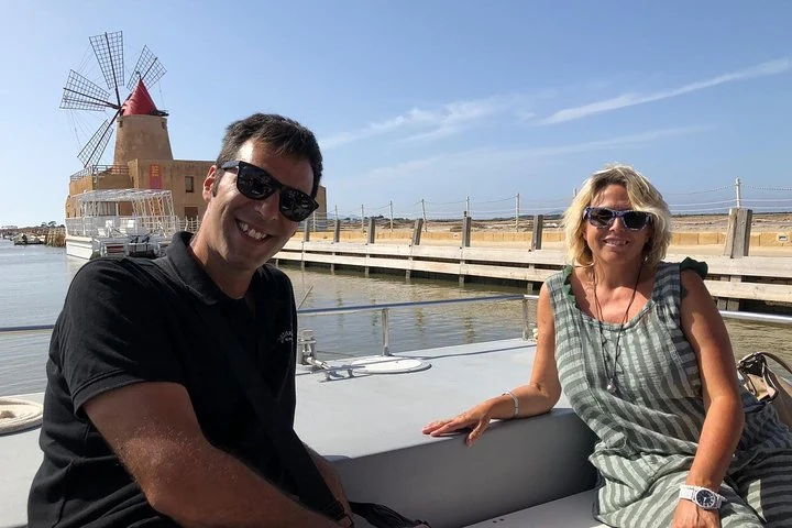 Deux visiteurs devant un moulin et l’embarcadère des salines de Marsala