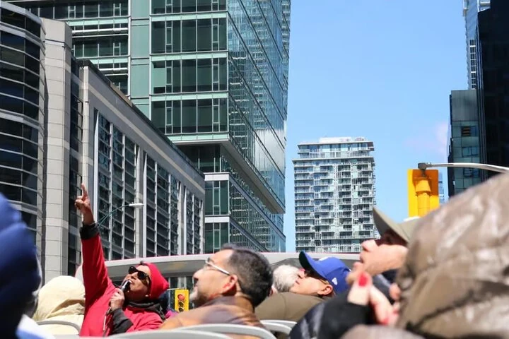 Pasajeros de un autobús turístico abierto entre edificios de Toronto