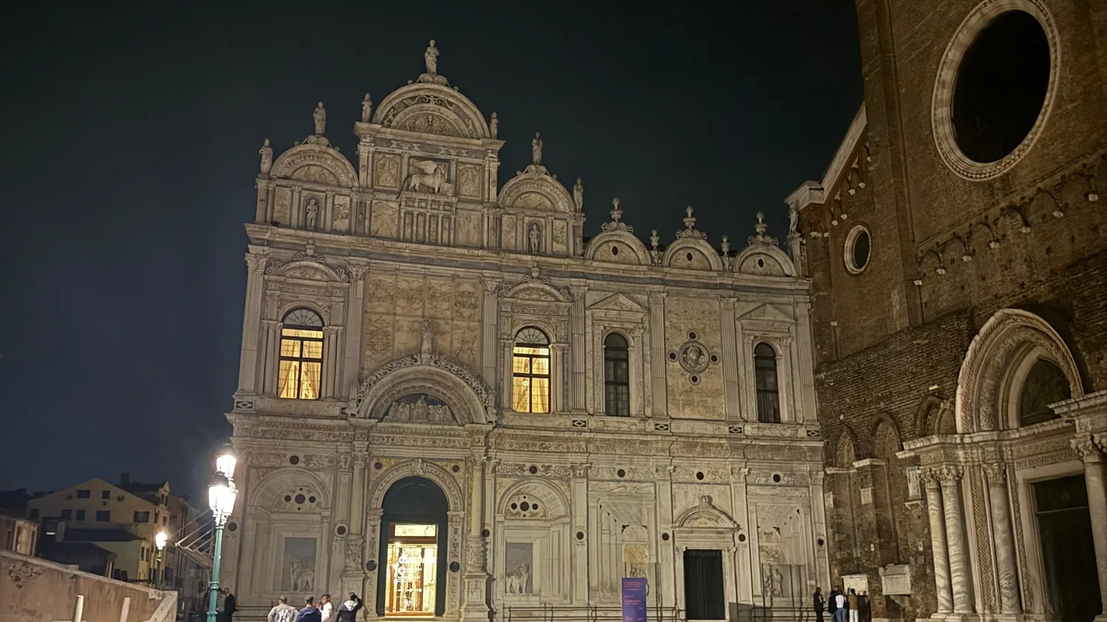 Fußgänger auf einem beleuchteten Platz in Venedig bei Nacht