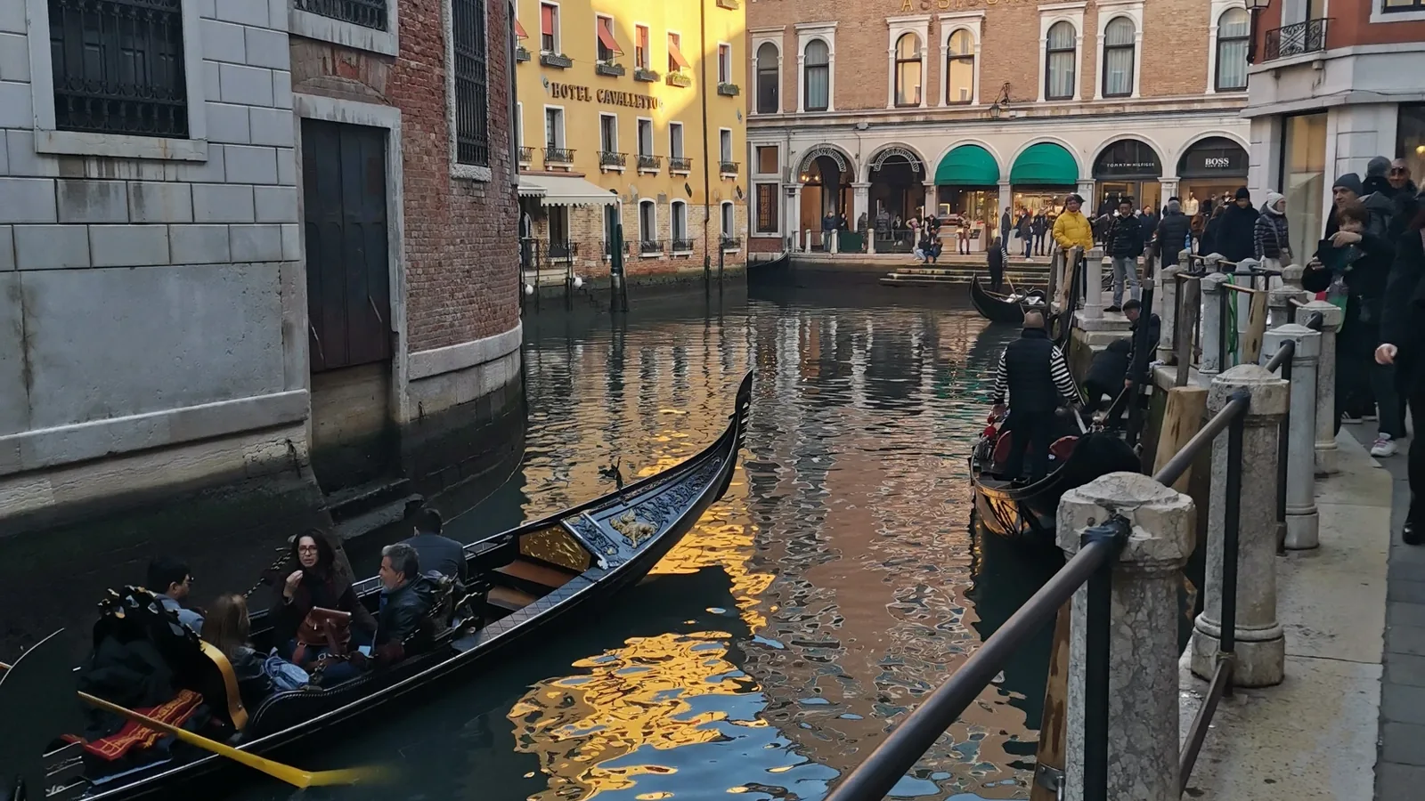 Venice canal with gondolas, pedestrians and buildings beside the water