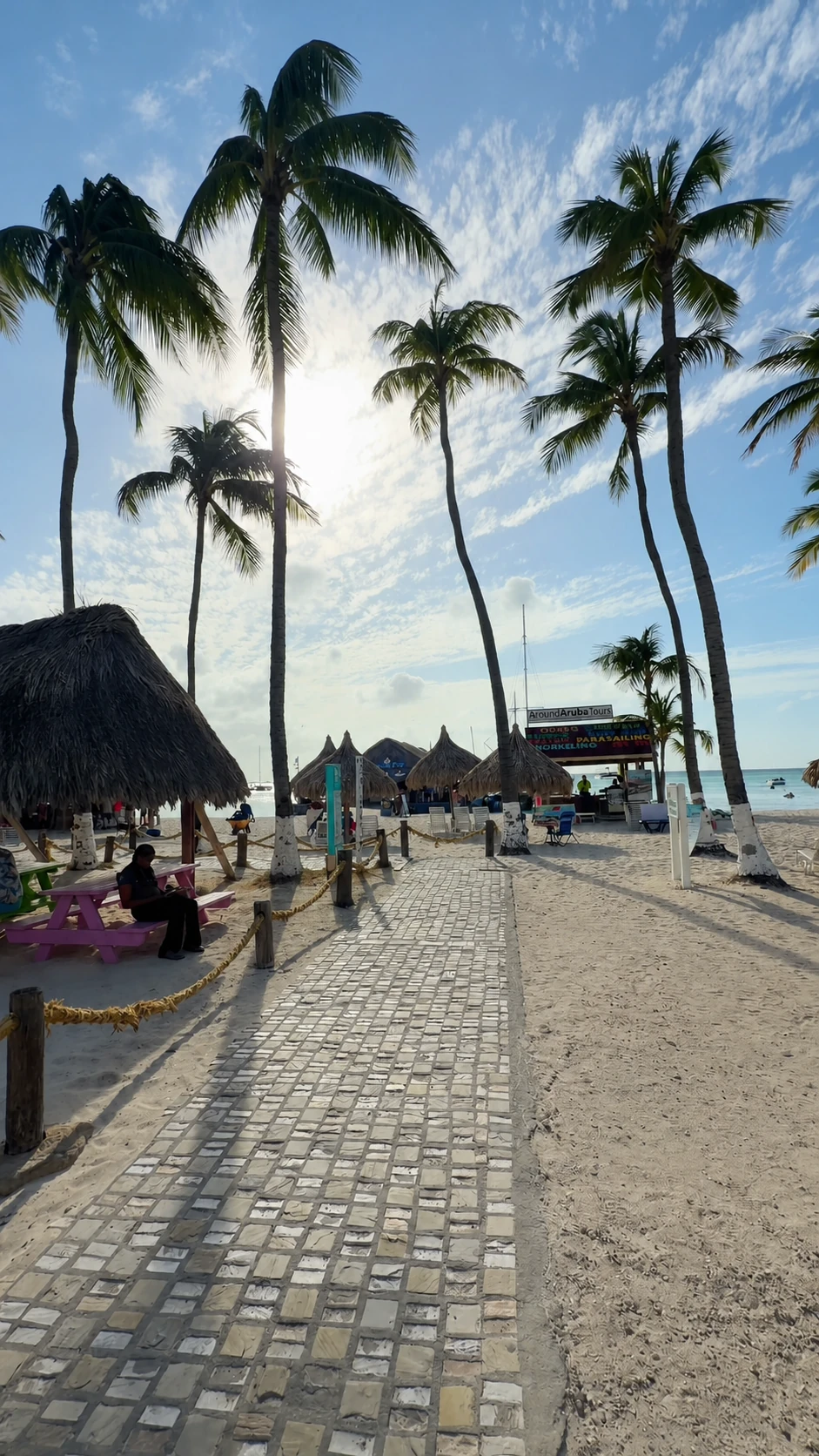 Allée bordée de palmiers et palapas à Palm Beach, Aruba