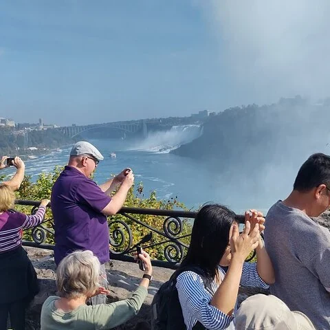 Des visiteurs photographient les chutes près d'une balustrade.