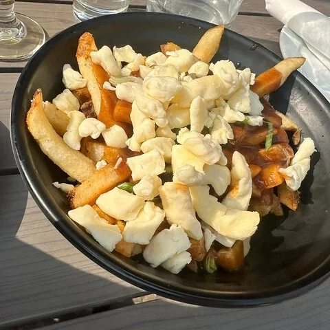 Eine schwarze Schüssel enthält Pommes mit zahlreichen hellen Stücken darauf.
