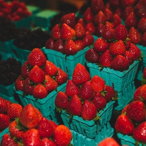 Körbe mit roten Erdbeeren an einem Stand.