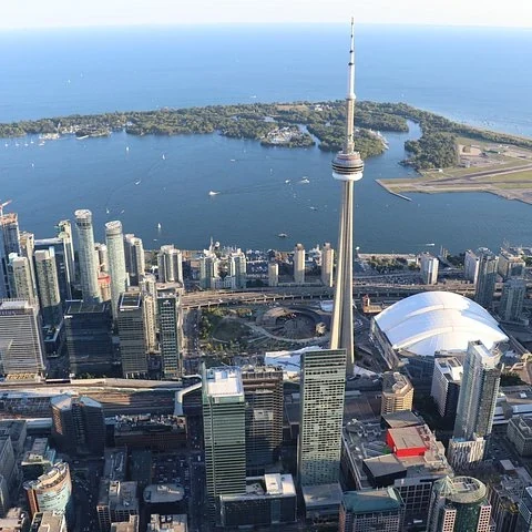 Luftaufnahme des CN Tower, von Gebäuden, einer weißen Kuppel und dem Wasser.
