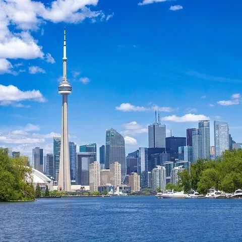 Der CN Tower und Gebäude am Wasser unter blauem Himmel mit Wolken.